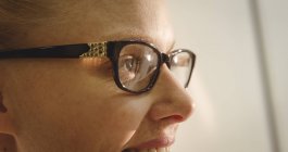 Primo piano di una cliente sorridente che indossa occhiali in negozio ottico — Foto stock