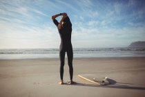 Rückansicht eines Mannes mit Surfbrett beim Training am Strand — Stockfoto