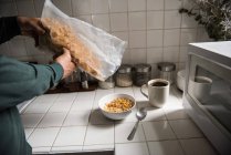 Средняя часть человека наливает зерновые в миску дома — стоковое фото