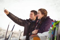 Happy skier couple clicking a selfie in ski resort — Stock Photo