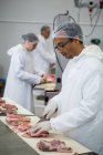 Metzger schneidet Fleisch in Fleischfabrik — Stockfoto