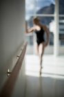 Ballerina stretching on a wall while practicing ballet dance in the studio — Stock Photo