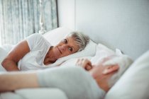 Senior couple lying on bed in bedroom — Stock Photo