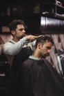 Peluquería peinando el cabello del cliente en la barbería - foto de stock