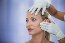 Mãos de médico examinando rosto paciente feminino para tratamento cosmético — Fotografia de Stock