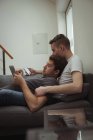 Гей пара використовує цифровий планшет і мобільний телефон, лежачи на дивані вдома — стокове фото