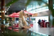 Жінка має каву в зоні очікування в терміналі аеропорту — стокове фото