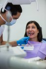 Dentiste examinant patiente avec des nuances de dents à la clinique dentaire — Photo de stock