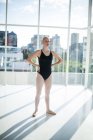 Балерина стоит с руками на талии в студии — стоковое фото
