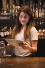 Bartender feminino usando tablet digital no balcão de bar — Fotografia de Stock
