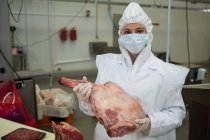 Портрет м'ясника-жінки, що тримає м'ясо на м'ясному заводі — стокове фото