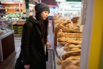 Mulher olhando para vários pães no balcão da padaria no supermercado — Fotografia de Stock