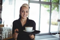 Ritratto di cameriera in piedi con tazza di caffè nel caffè — Foto stock