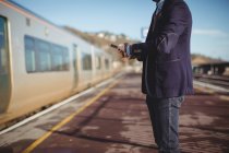 Cropped view of businessman checking time on watch at railway station — Stock Photo