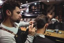 Customer getting hair trimmed with trimmer in barber shop — Stock Photo
