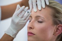 Close-up of female patient receiving botox injection on forehead — Stock Photo