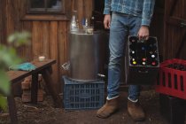 Mann trägt selbstgebackene Bierflaschen in Kiste in Hausbrauerei — Stockfoto