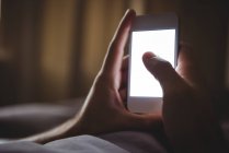 Крупный план мужских рук с помощью мобильного телефона в спальне — стоковое фото