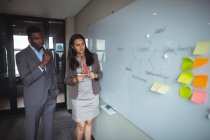 Geschäftsmann und ein Kollege schauen auf Whiteboard im Konferenzraum im Büro — Stockfoto