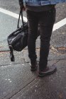 Sección baja del hombre con bolso de pie en la calle - foto de stock