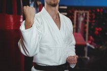 Sección media del jugador de karate que realiza postura de karate en el estudio de fitness - foto de stock