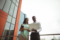 Бизнесмен и коллега обсуждают за ноутбуком в офисе — стоковое фото