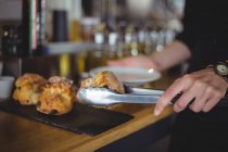 Nahaufnahme der Kellnerin, die Muffin in einem Teller am Tresen im Café serviert — Stockfoto