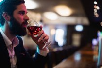 Homme d'affaires prenant un verre de vin dans le comptoir du bar au bar — Photo de stock