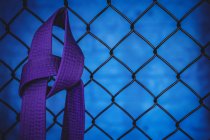 Close-up of karate purple belt hanging on wire mesh fence in fitness studio — Stock Photo