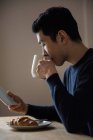 Чоловік використовує цифровий планшет під час сніданку вдома — стокове фото