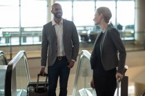 Geschäftsleute interagieren miteinander, während sie auf der Rolltreppe am Flughafen-Terminal nach oben steigen — Stockfoto