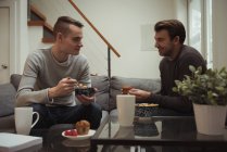 Pareja gay desayunando juntos en casa - foto de stock