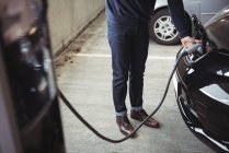 Низька частина людини заряджає автомобіль на зарядній станції електромобіля — стокове фото