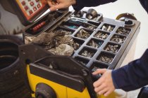 Mãos de mecânico usando dispositivo de diagnóstico eletrônico e várias ferramentas na garagem de reparação — Fotografia de Stock