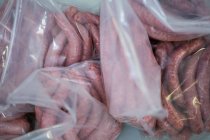 Primo piano delle salsicce crude nel sacchetto di imballaggio in plastica presso la fabbrica di carne — Foto stock