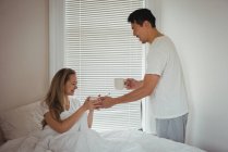 Homme servant le petit déjeuner à femme dans la chambre à coucher à la maison — Photo de stock