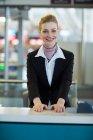 Retrato del asistente de facturación sonriente de la aerolínea en el mostrador en la terminal del aeropuerto - foto de stock