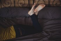 Gekreuzte Beine einer Frau, die zu Hause im Schlafzimmer auf dem Bett liegt — Stockfoto