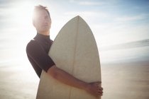 Surfista premuroso in piedi con tavola da surf sulla spiaggia — Foto stock