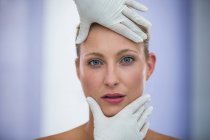 Mani del medico che esamina il viso femminile paziente per il trattamento cosmetico — Foto stock