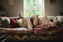 Frau liegt zu Hause auf dem Sofa im Wohnzimmer — Stockfoto