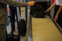 Female staff checking passengers luggage on conveyor belt in airport — Stock Photo