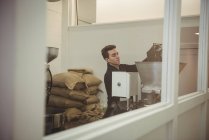 Uomo versando chicchi di caffè in macchina torrefazione caffè in caffetteria — Foto stock
