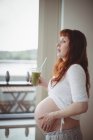 Mulher grávida cuidadosa segurando vidro de suco em casa — Fotografia de Stock