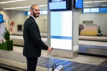 Портрет бизнесмена, стоящего с багажной сумкой в аэропорту — стоковое фото