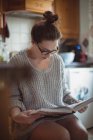 Donna che legge libro in cucina a casa — Foto stock