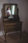 Reflection of pregnant woman looking through window in bedroom at home — Stock Photo