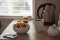 Breakfast cereals with coffee cup and mobile phone on kitchen worktop at home — Stock Photo
