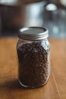 Gros plan d'un pot de grains de café torréfiés — Photo de stock