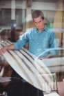 Homme sélectionnant une planche de surf dans un magasin derrière la fenêtre — Photo de stock